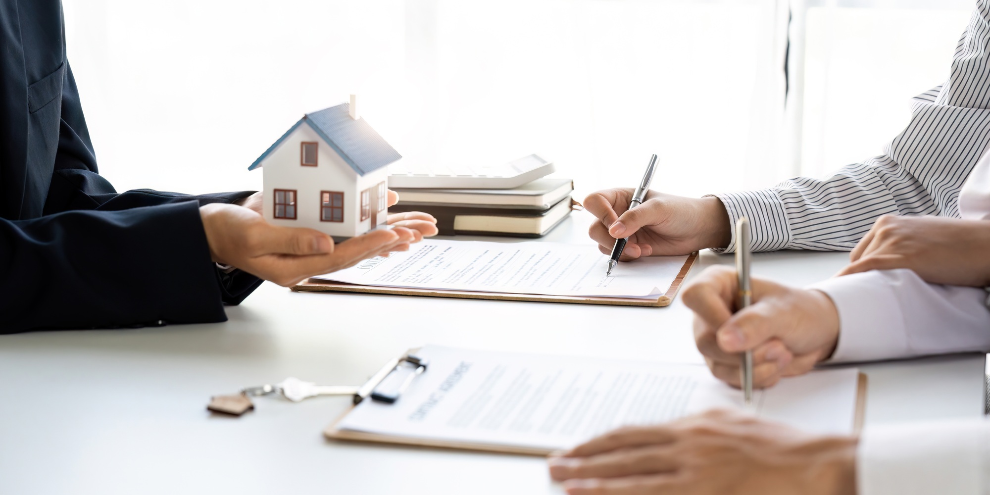 Real estate agent with couple closing a deal and signing a contract.